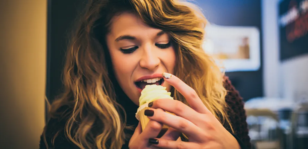 A woman eating a cupcake in a restaurant.